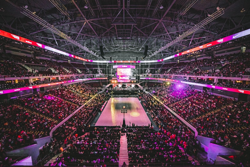 NBA篮球馆内灯光璀璨，球员正在进行赛前热身准备，观众席逐渐满座